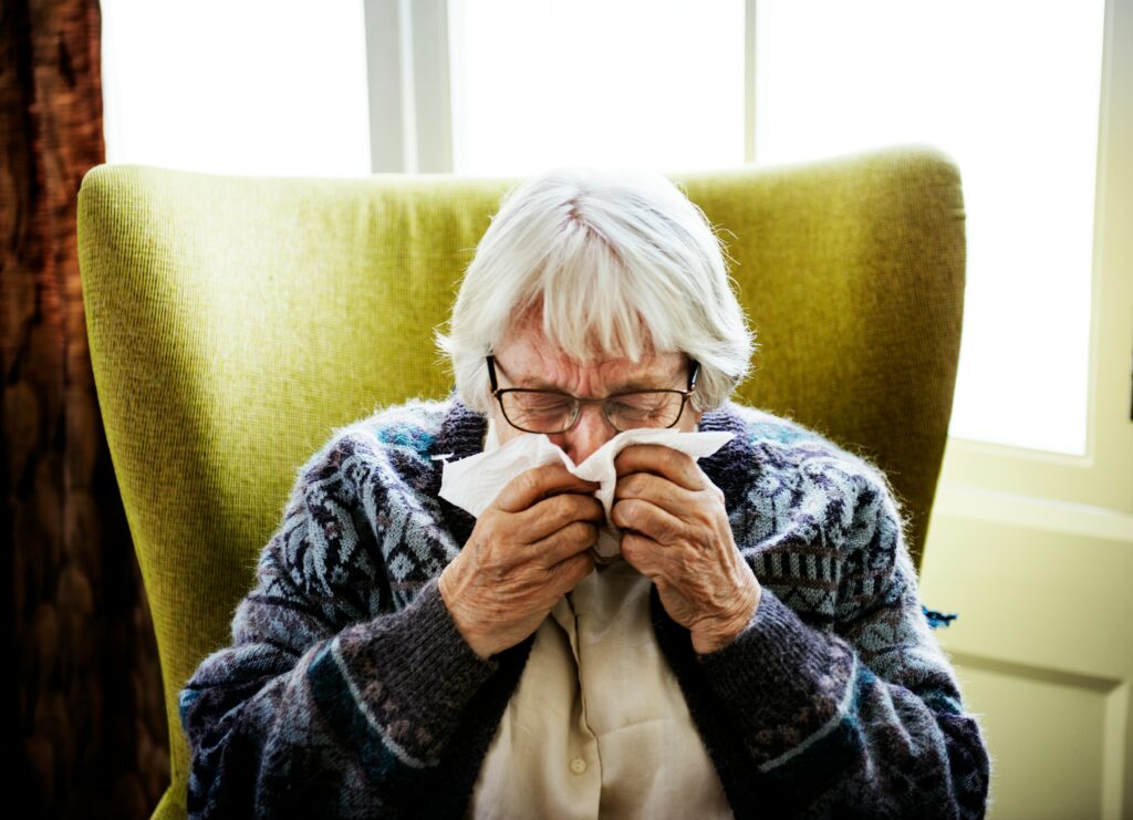 Older person sneezing into a tissue
